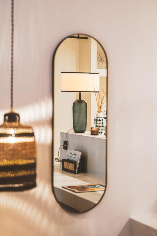 un miroir reflétant une table avec une lampe sur celle-ci, dans l'établissement La Suite des Bouchonniers, à Saint-Tropez