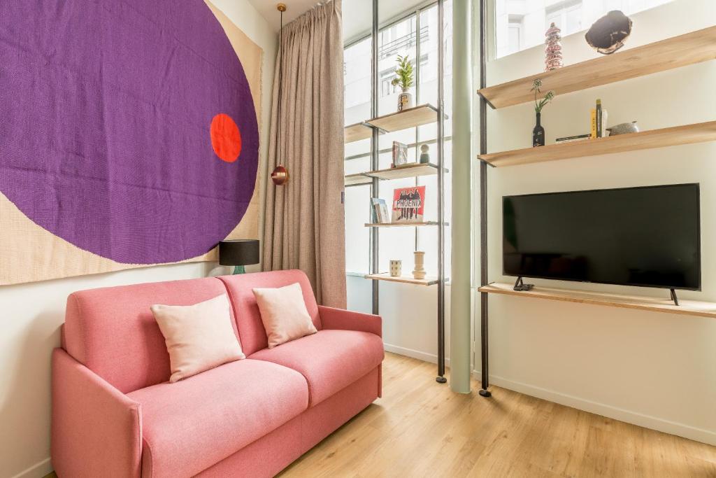 sala de estar con sofá rosa y TV en Appartement Panthéon - Feuillantines, en París