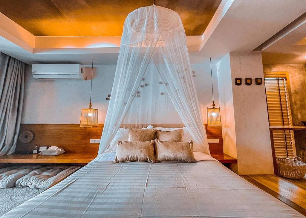 a bedroom with a bed with a mosquito net at The Parlour Krabi in Klong Muang Beach