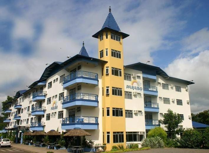 un grand bâtiment jaune avec une tour d'horloge dans l'établissement Hotel Paraiso, à Piratuba