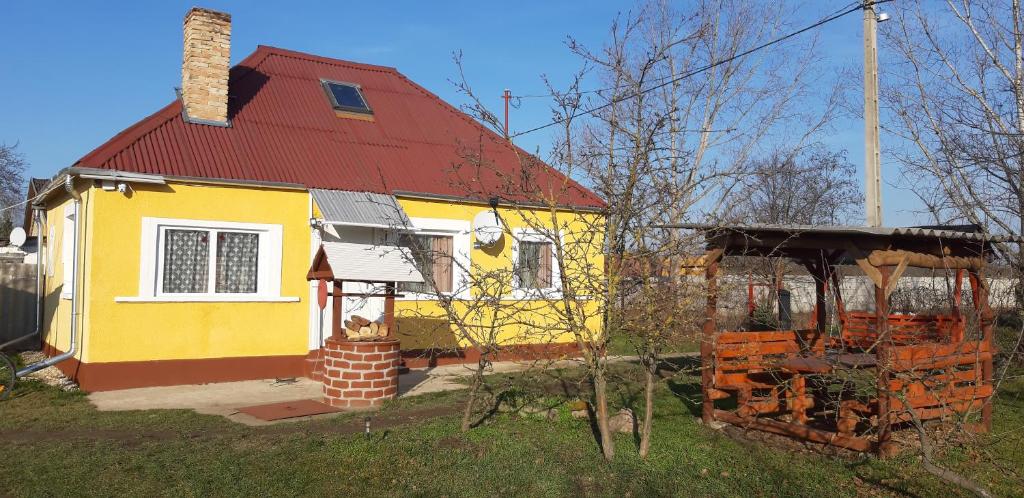 una casa gialla e rossa con tetto rosso di Akácvirág Vendégház a Ács