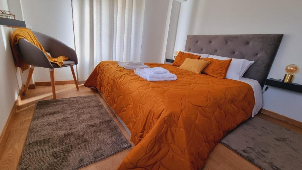 1 dormitorio con 1 cama con sábanas de color naranja y silla en CASAS DO CÔA - Casa Santa Luzia en Vila Nova de Foz Cõa