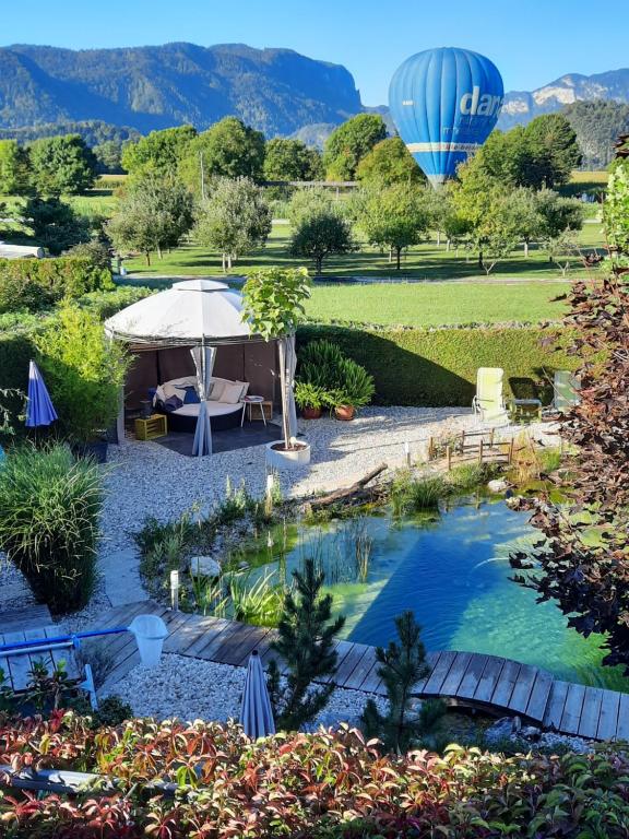 a hot air balloon flying over a garden with a pool at Garden Paradise Bled Apartments - garden, pond and castle view in Bled