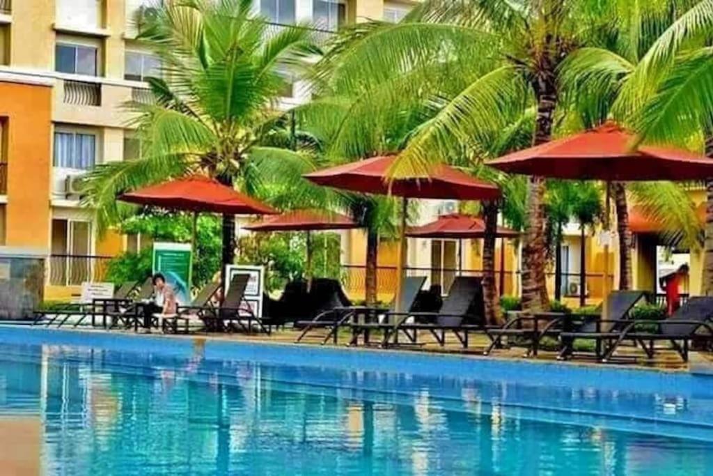 a pool with chairs and umbrellas next to a hotel at 2BR Casa Mia Sanremo Oasis Cebu in Talisay