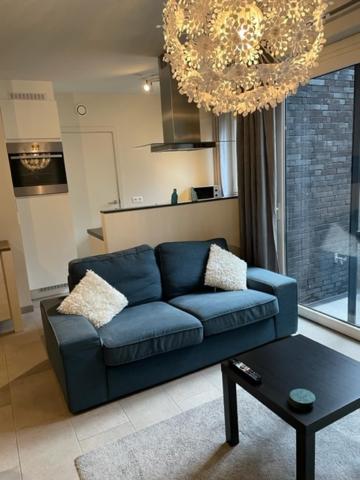 een blauwe bank in een woonkamer met een kroonluchter bij Apartments James Ensor in Oostende