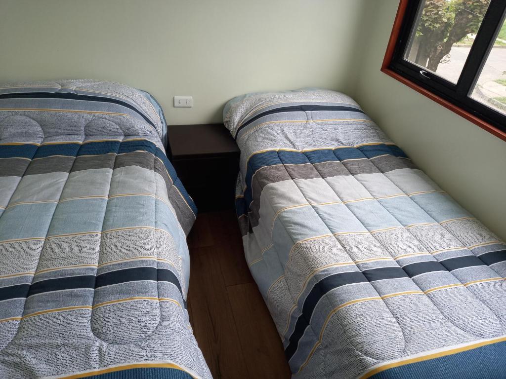 twee bedden naast elkaar in een kamer bij Cabañas y Departamentos Las Palmas, Temuco Depto 1 in Temuco