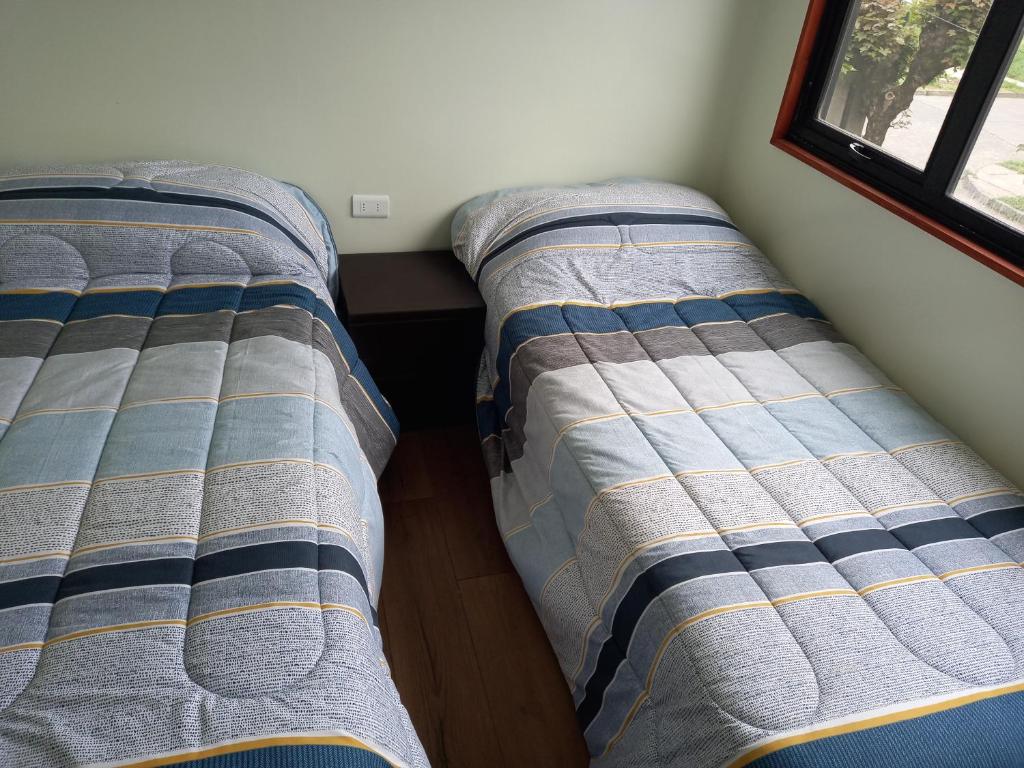 two beds sitting next to each other in a room at Cabañas y Departamentos Las Palmas, Temuco Depto 1 in Temuco