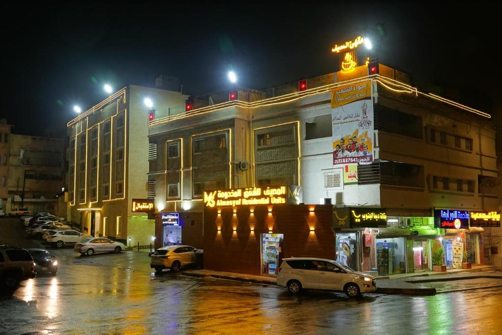un edificio con coches estacionados en un estacionamiento por la noche en شقق المصيف للوحدات السكنية, en Abha