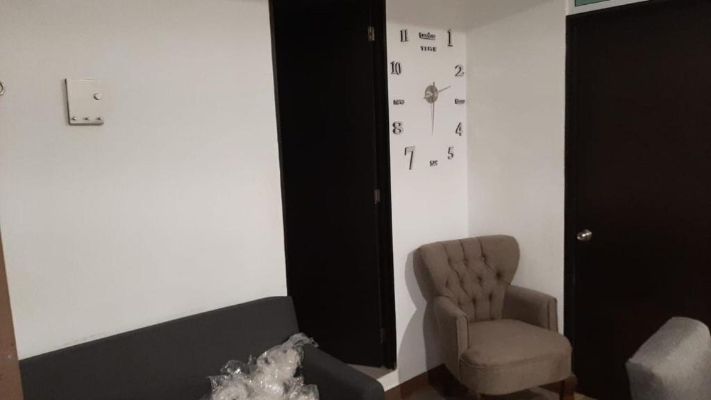 una habitación con una silla y un reloj en la pared en Ponzanelli, en Ciudad de México