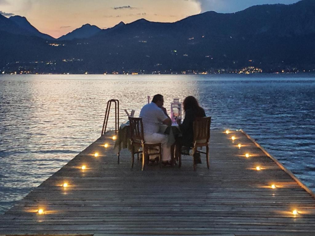 una pareja sentada en una mesa en un muelle en un lago en Hotel Merano, en Brenzone sul Garda