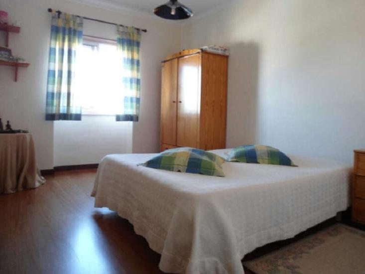 a bedroom with a bed and a cabinet and a window at Quartos no centro de Torres Vedras in Torres Vedras