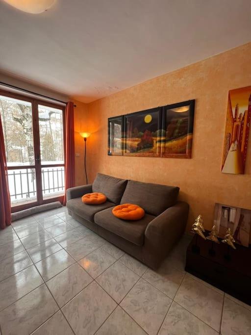 a living room with a couch with two orange pillows at Calda e accogliente Limone in Limone Piemonte