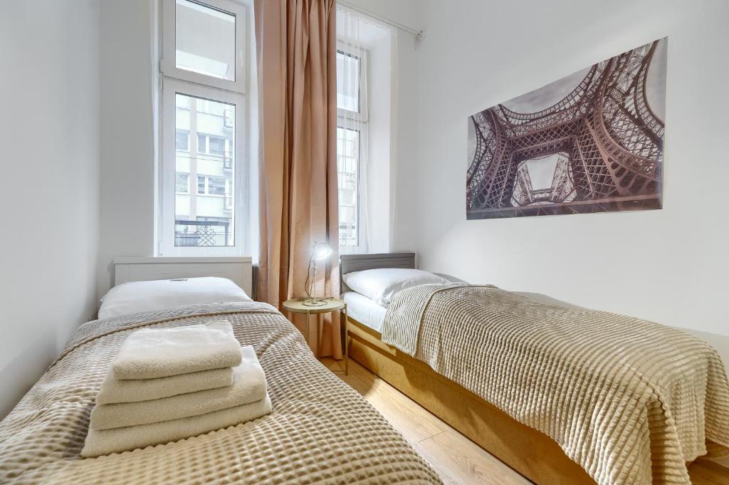 twee bedden in een kamer met twee ramen bij Kamienica Centrum Apartament nr 3 in Szczecin