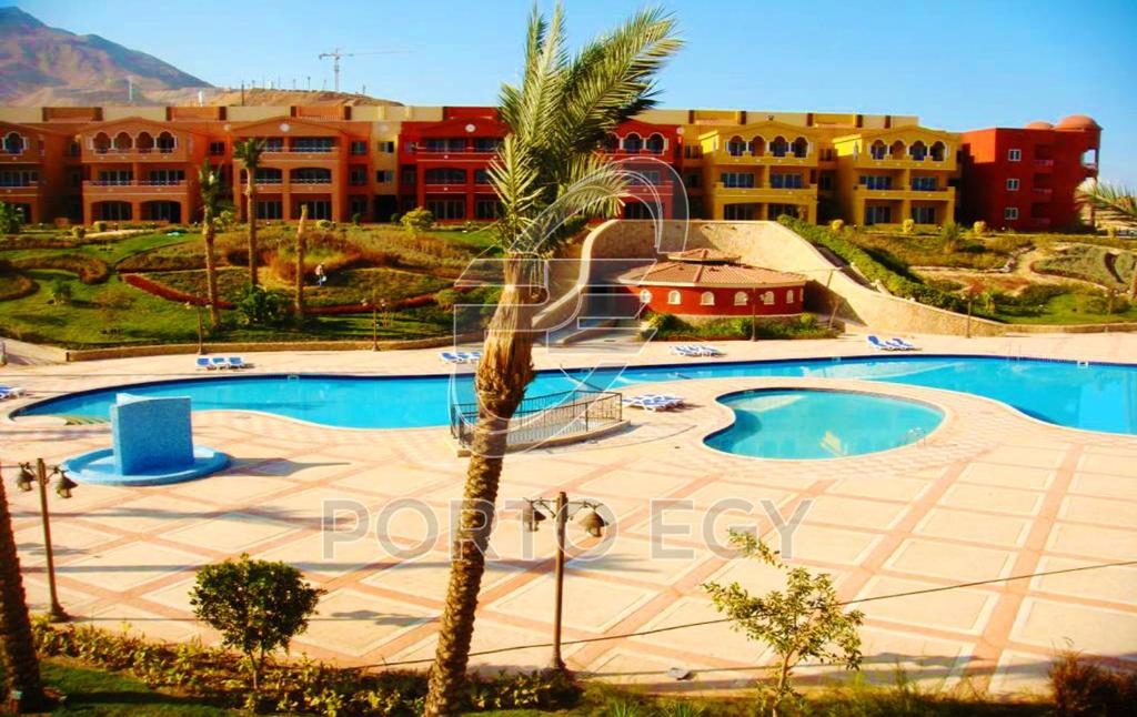 a resort with a swimming pool and a palm tree at 2 Bedroom Ground floor Chalet with Terrace - Porto Sokhna - Families Only in Ain Sokhna