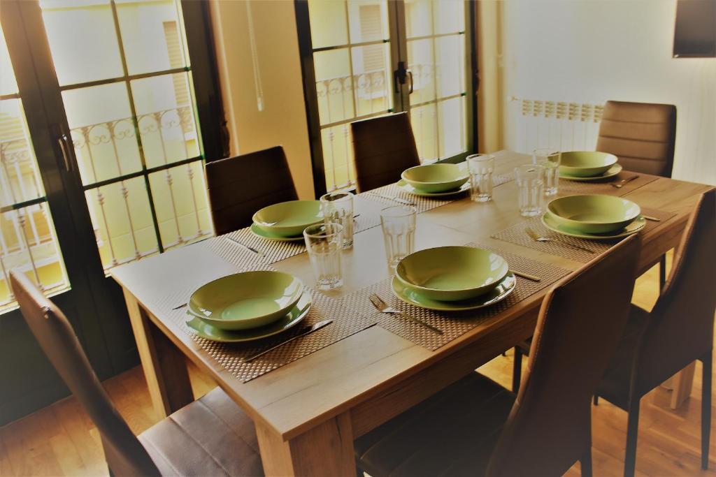 a wooden table with green plates and dishes on it at Vergarillas 2 in Ávila