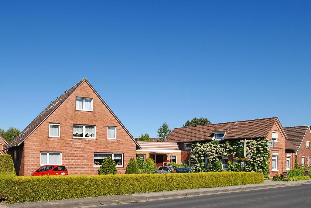 une maison en briques avec des voitures garées devant elle dans l'établissement Pension Nordlicht, à Esens