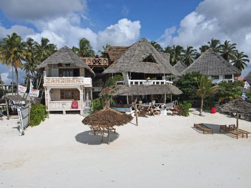 een resort op het strand met stoelen en parasols bij Sweet Beach Apartments in Jambiani