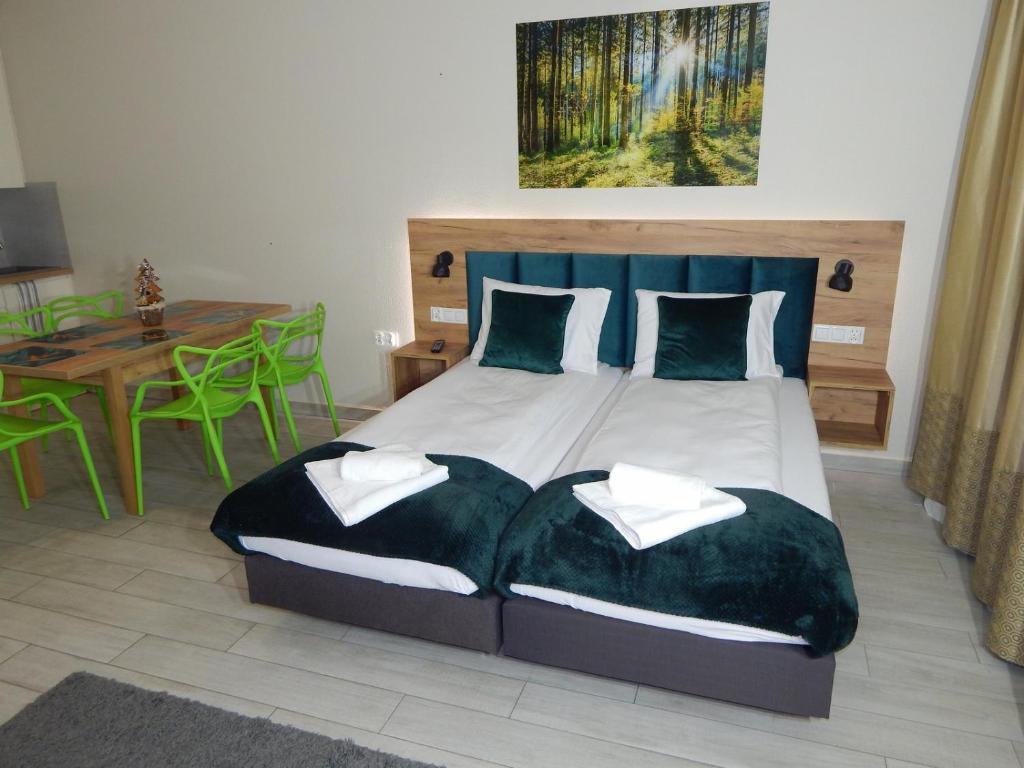 Un dormitorio con una cama con almohadas verdes y una mesa. en AGAT Apartament Czarna Góra en Sienna