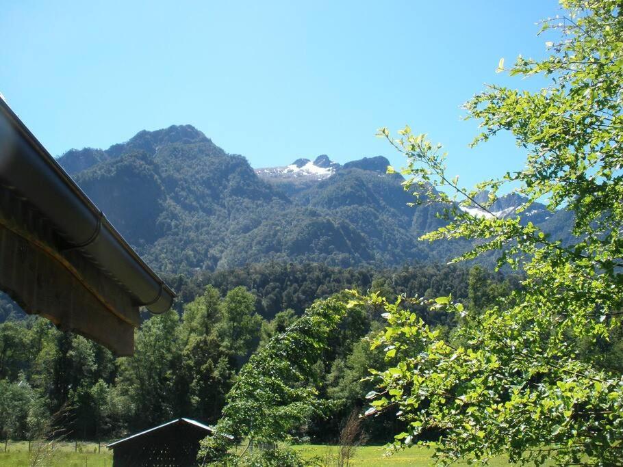 a view of a mountain range with trees and a house at Cabaña Arriendo Llifen in Futrono
