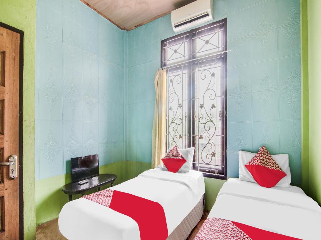 a room with two beds and a window at OYO 92055 Nirvana Homestay Syariah in Bangkinang
