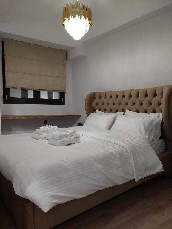 a bedroom with a large bed with white sheets and a chandelier at October Luxury Apartments Studio in Ioannina