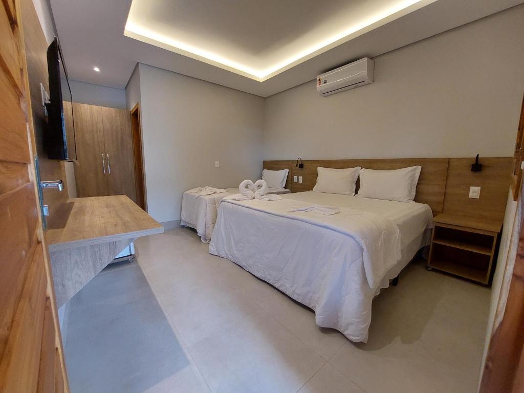 a hotel room with two beds and a sink at Pousada e Restaurante Valle dos Ventos in Chapada dos Guimarães