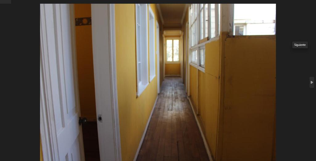 un pasillo vacío con paredes amarillas y suelo de madera en Casapuerto, en Valparaíso