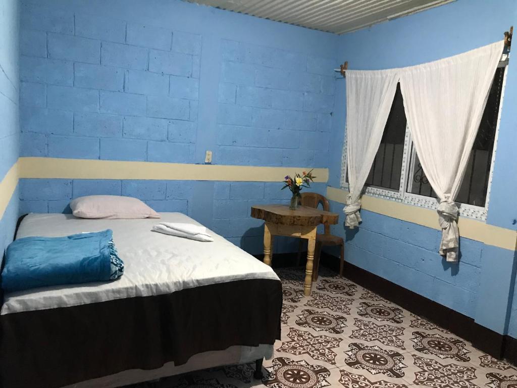 Dormitorio azul con cama y ventana en Casa Julián Cotuc, en San Juan La Laguna