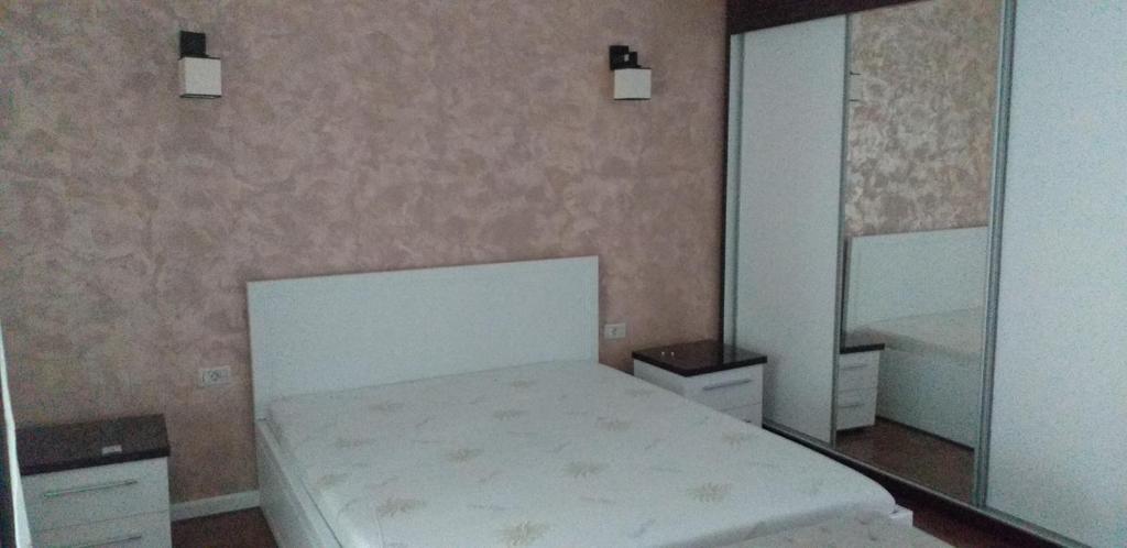 een slaapkamer met een wit bed en een spiegel bij Apartament lux in Roman