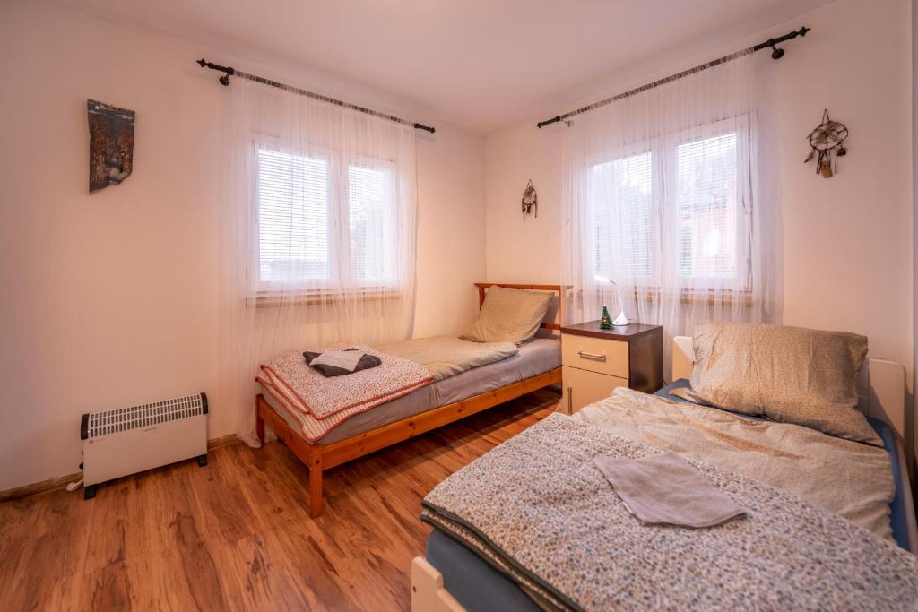 a bedroom with two beds and two windows at Domek bez zegara in Lądek-Zdrój