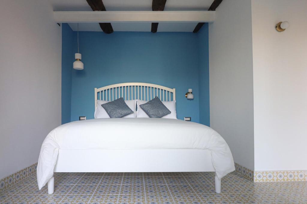 ein Schlafzimmer mit einem weißen Bett mit blauen Wänden in der Unterkunft La Casa del Bosco - Unique two storey House with garden in Neapel