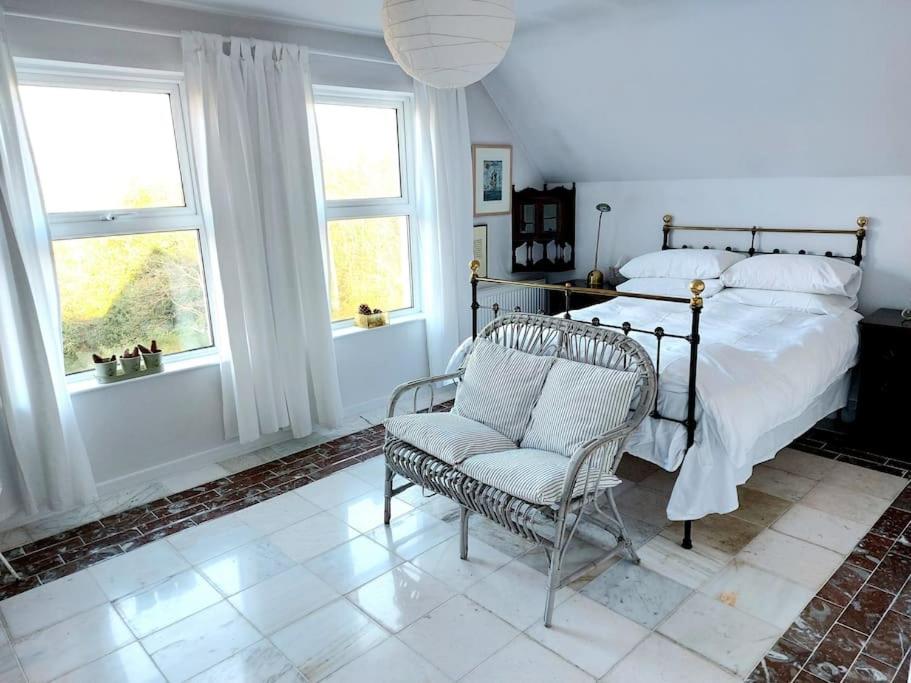 um quarto com uma cama, uma cadeira e janelas em Stunning apartment set in private native woodland em Ramelton