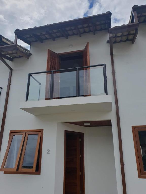 ein weißes Haus mit einem Balkon und einer Tür in der Unterkunft Casas a 5 min do Centro Histórico in Paraty