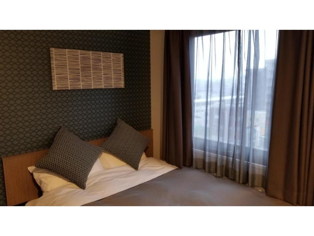 a bedroom with a bed with pillows and a window at Sun Royal Utsunomiya - Vacation STAY 02522v in Utsunomiya