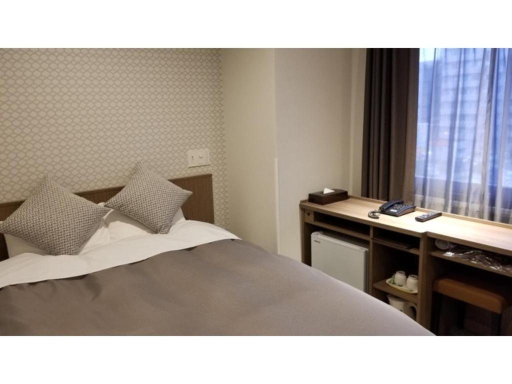 a bedroom with a bed and a desk and a window at Sun Royal Utsunomiya - Vacation STAY 02512v in Utsunomiya