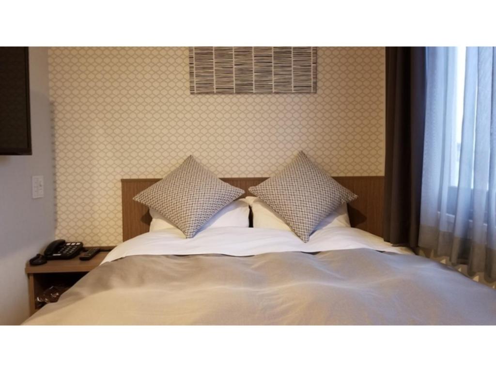 a bed with two pillows on top of it at Sun Royal Utsunomiya - Vacation STAY 02516v in Utsunomiya