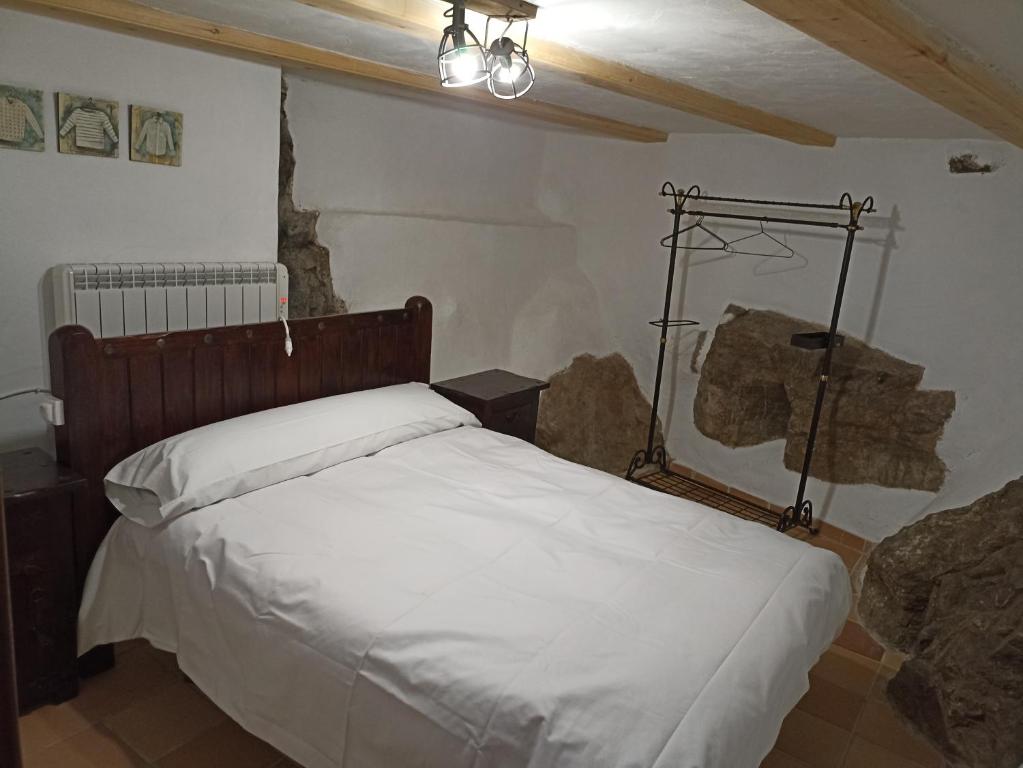Un dormitorio con una cama blanca con una lámpara. en Apartamento Valdelinares,Casa la roca, en Valdelinares