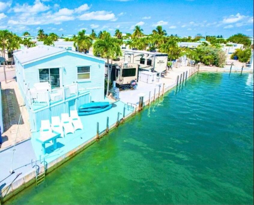 a blue house on a dock in the water at NAUTILUS...ocean front cottage retreat ~ in Cudjoe Key