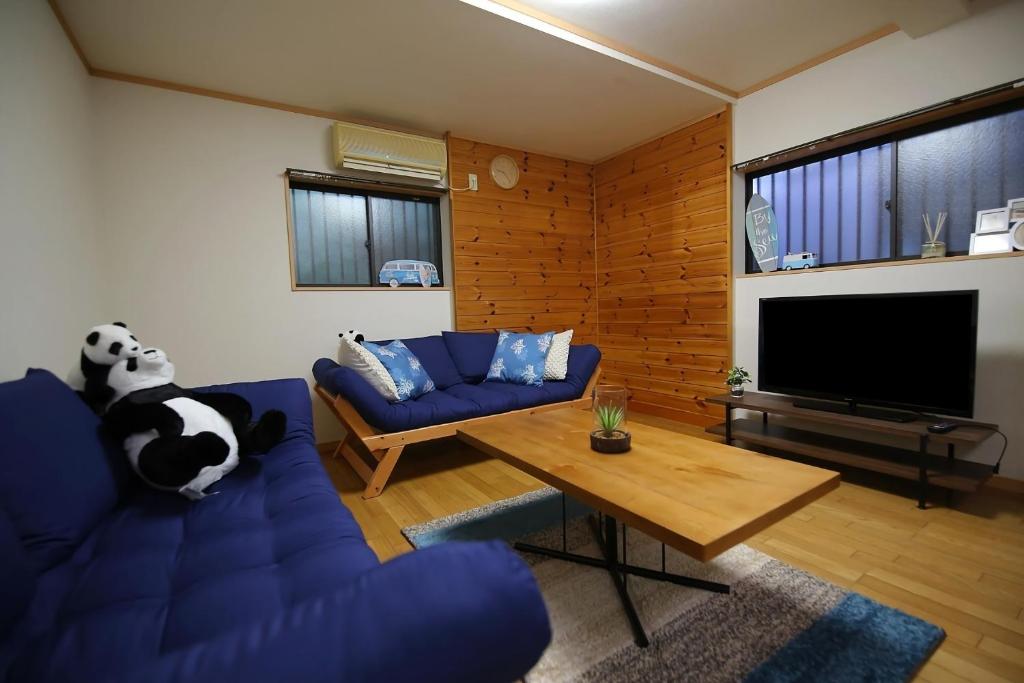 un soggiorno con divano blu e TV di Tokai Ryokan Ichigokan - Vacation STAY 29187v ad Atami