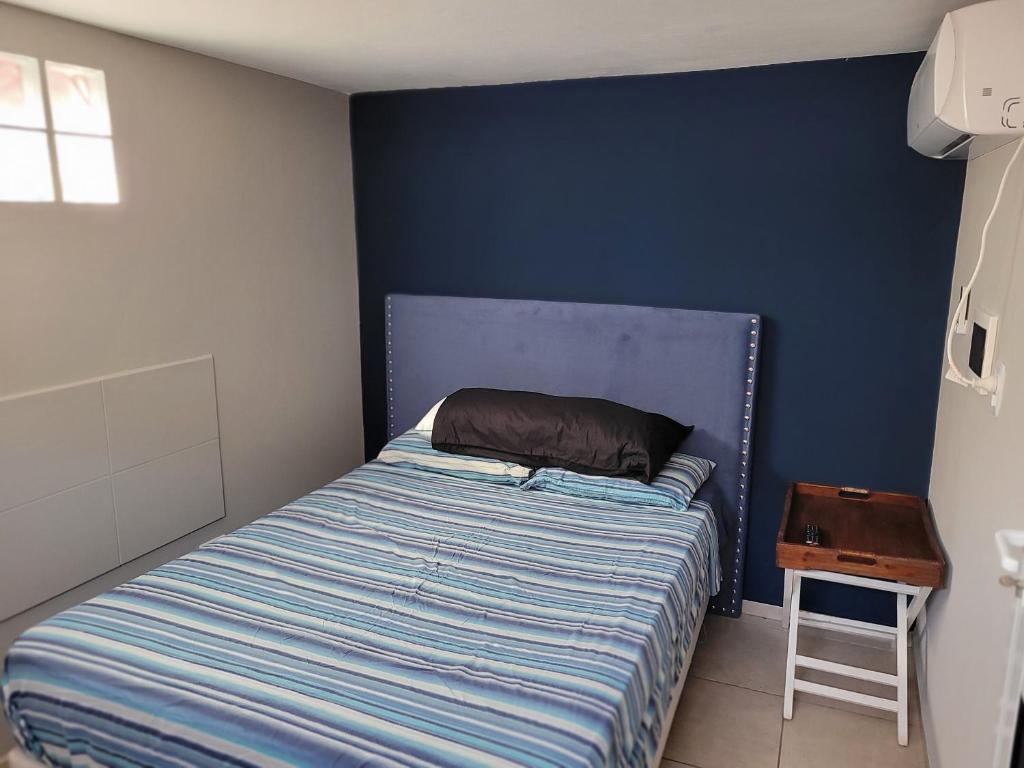 1 cama en un dormitorio con una pared azul en Aqua Duplex en Villa Carlos Paz