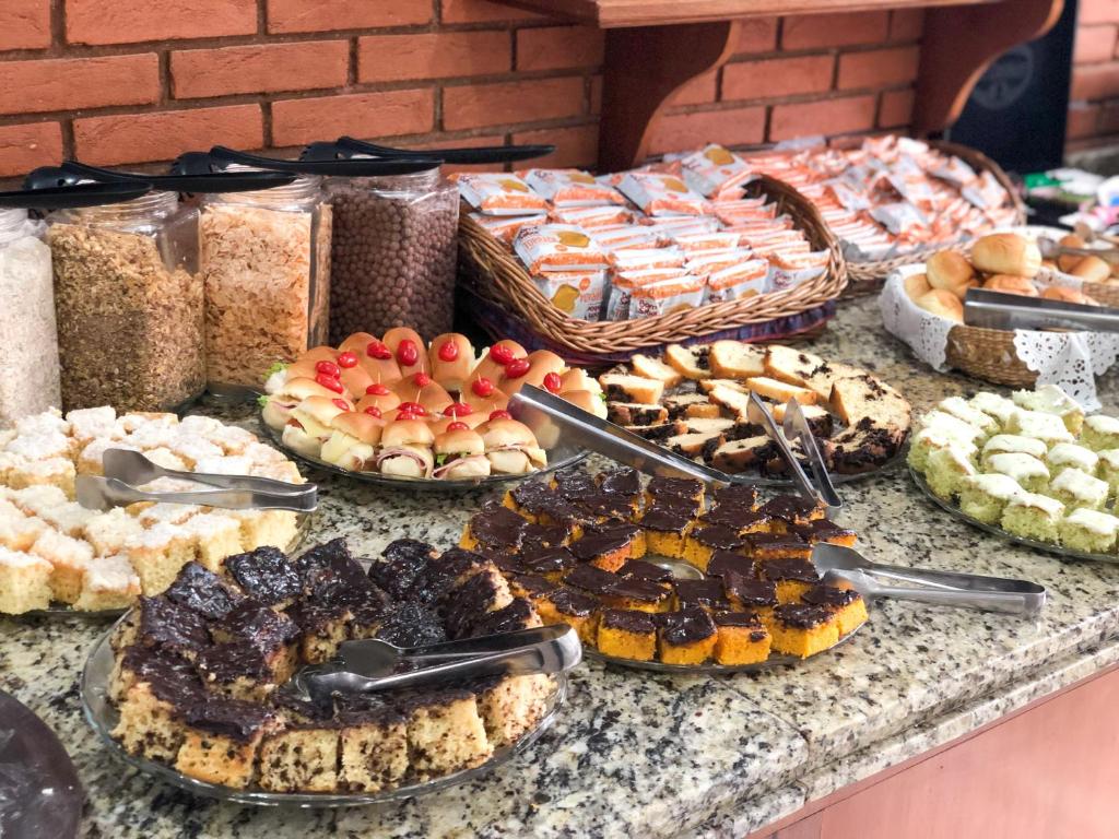 una mesa con diferentes tipos de pasteles y repostería en Hotel Garnier en Campos do Jordão