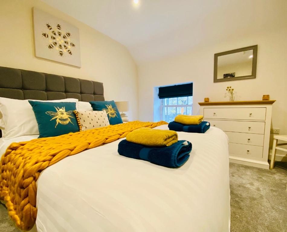 een slaapkamer met een groot wit bed met blauwe en gele kussens bij Rustic Retreats Jacks Cottage with Hot Tub & Alpaca Walking Experiences in Matlock