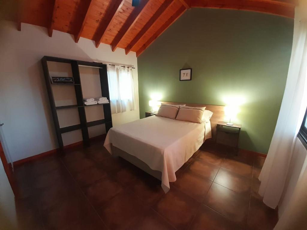 1 dormitorio con cama blanca y pared verde en Ikigai en Los Molles
