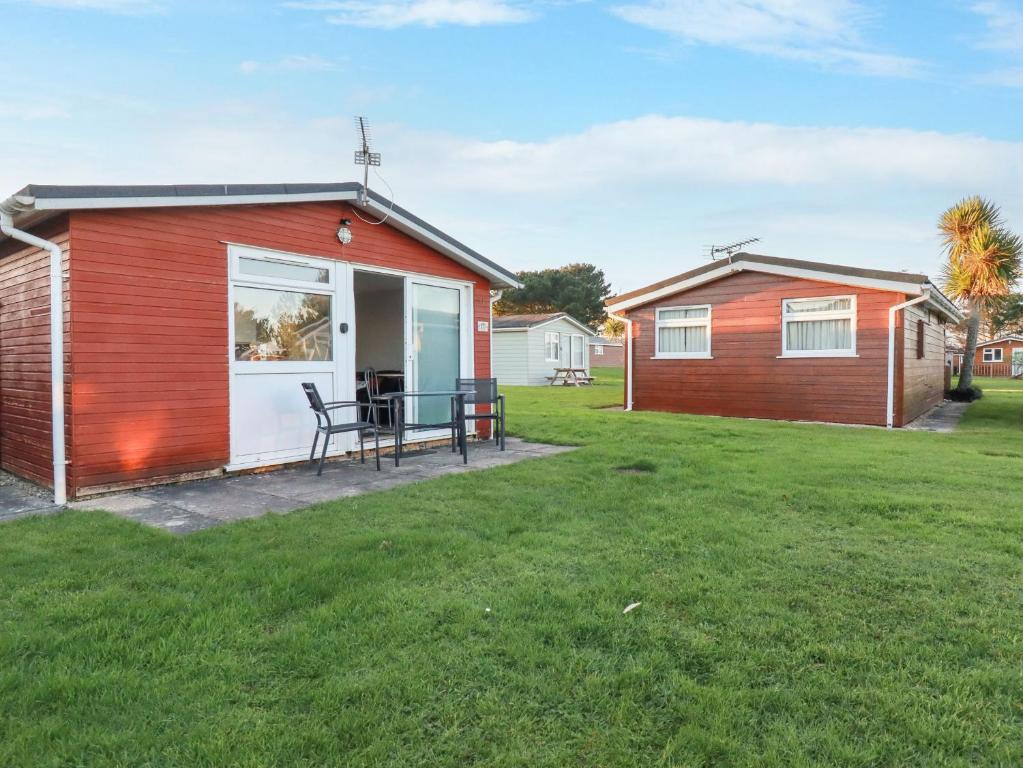 a red shed with a table in a yard at 171 Atlantic Bays in Padstow