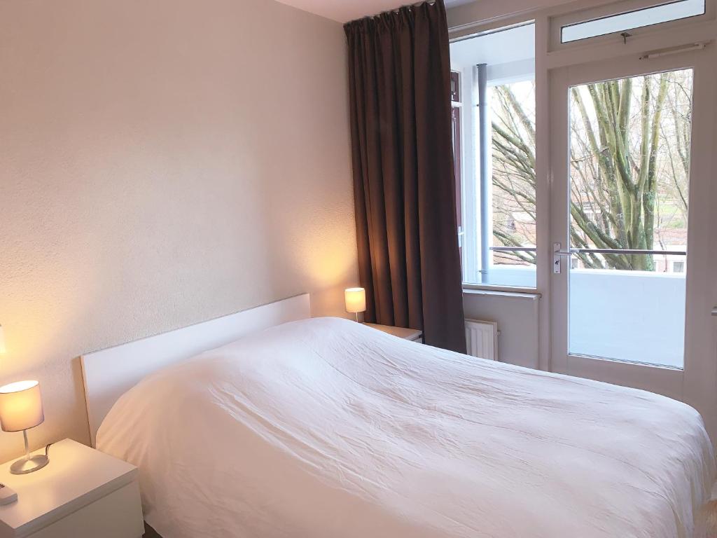 1 dormitorio con cama blanca y ventana en KeyCity Apt Near Amsterdam & The Hague, en Leiden