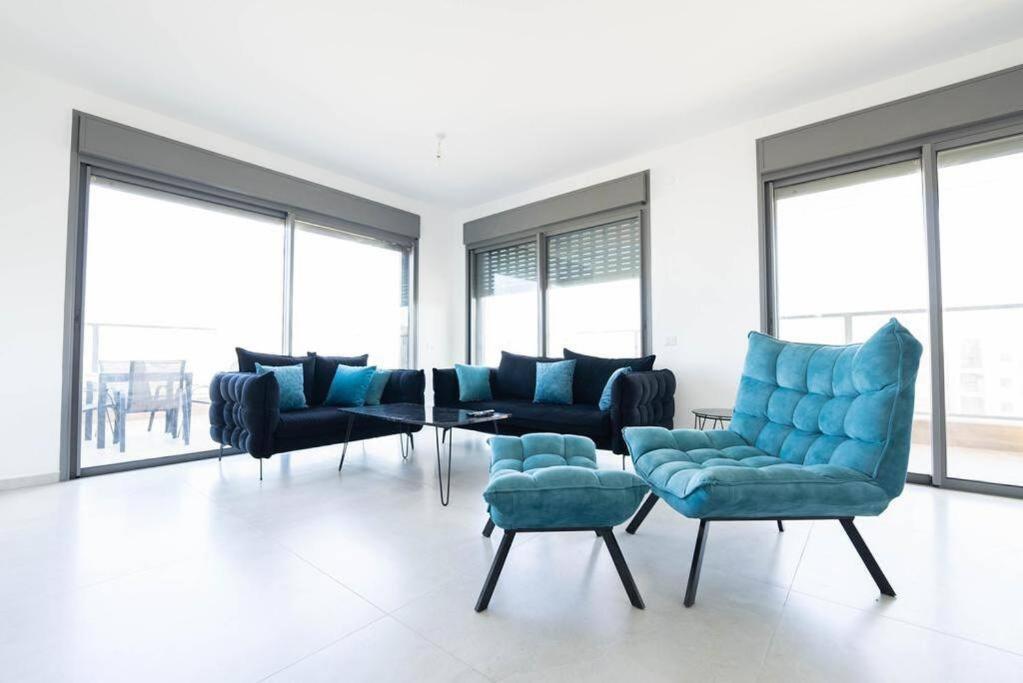 a living room with blue furniture and large windows at Luxury Penthouse 5 Rooms in Or Yehuda