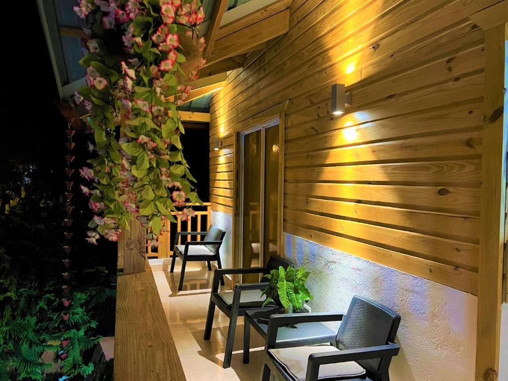 a patio with chairs and flowers on a wooden wall at Alaia Casa de campo By Hospedify Para 4 personas, cerca del Río, Naturaleza, BBQ y terraza familiar in Jarabacoa