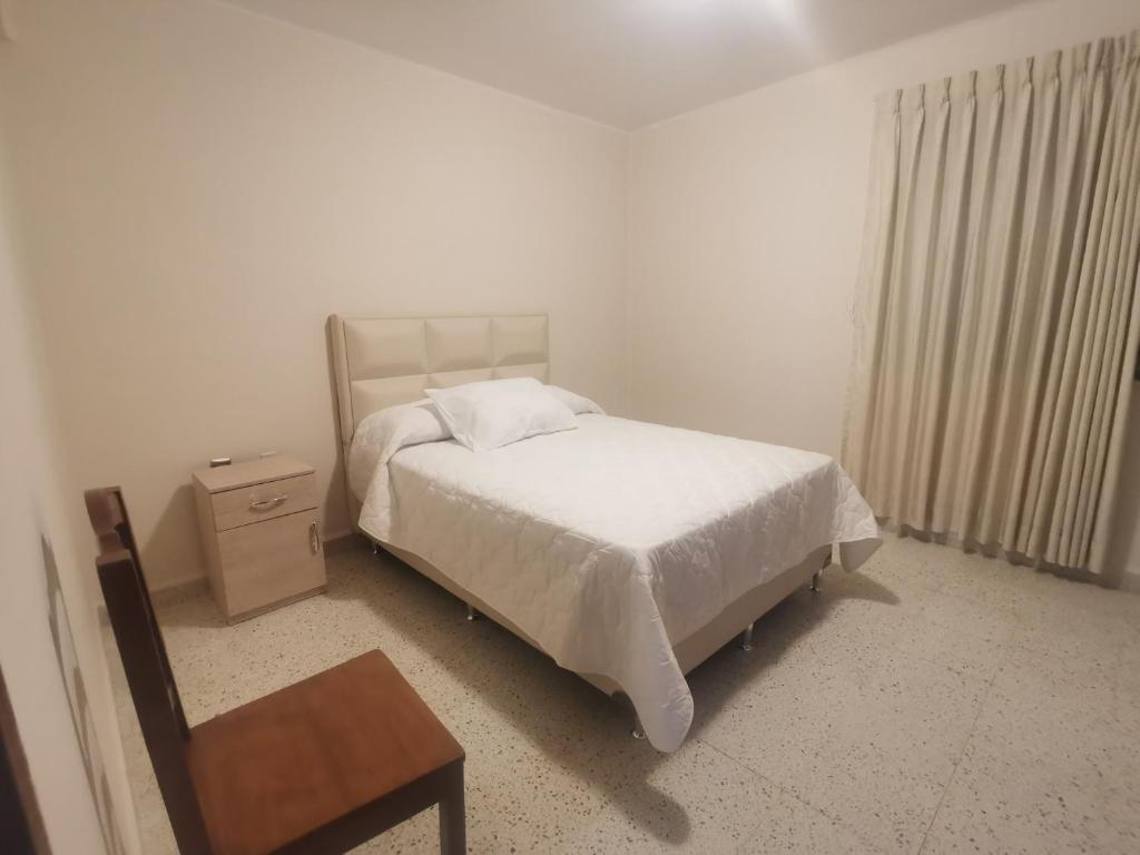 1 dormitorio con cama, mesita de noche y mesa en departamento céntrico y confortable, en Tarija