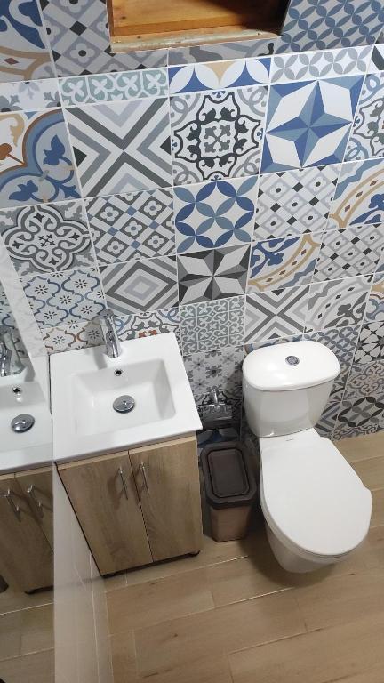 y baño con aseo, lavabo y azulejos. en Glamping VILLA - Nueva en Paipa, en Paipa