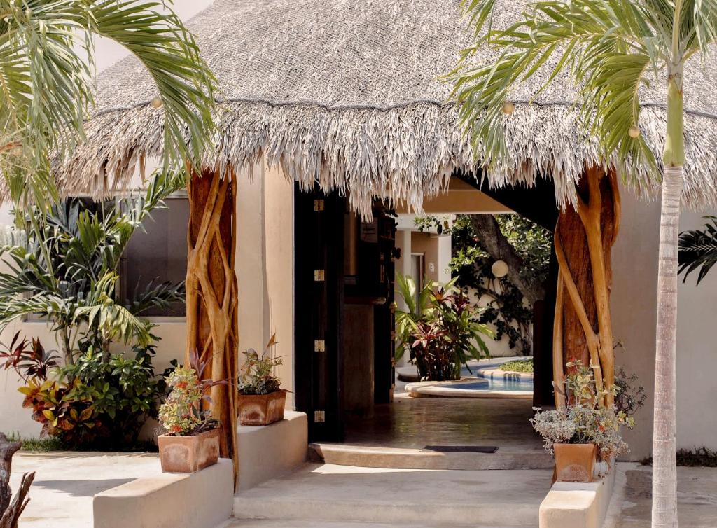 a resort entrance with palm trees and a thatch roof at Boutique Hotel Posada 06 Tulum in Tulum